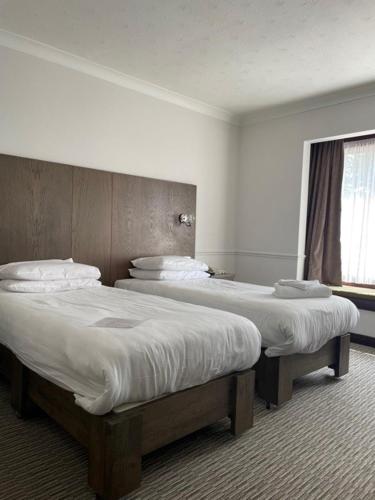 two twin beds in a room with a window at Best Western Ipswich Hotel in Ipswich