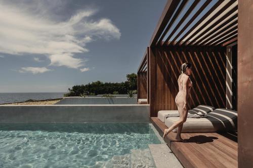a man standing on a bed next to a swimming pool at Meraviglia Slow Living in Preveza