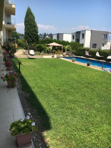 a yard with a swimming pool and a lawn with flowers at Sea Dream Rental Apartments in Varna City