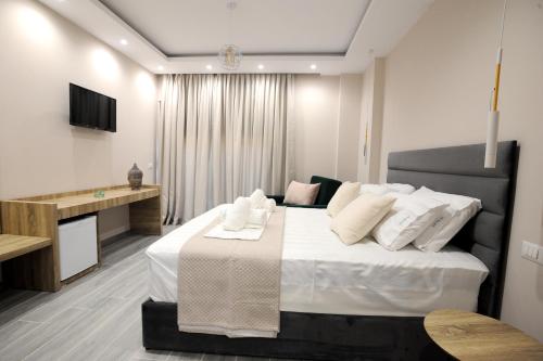 a bedroom with a large white bed and a television at AFRODITE SUITES in Sarandë