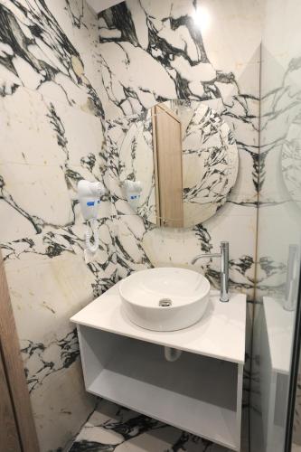 a bathroom with a sink and a marble wall at AFRODITE SUITES in Sarandë