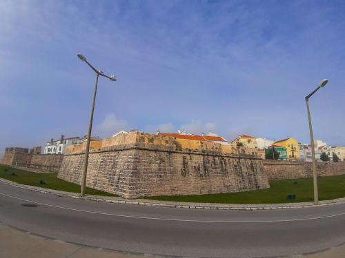 a stone wall with two street lights and houses at CASA do BATORÉU - BUARCOS 120 MT PRAIA in Figueira da Foz