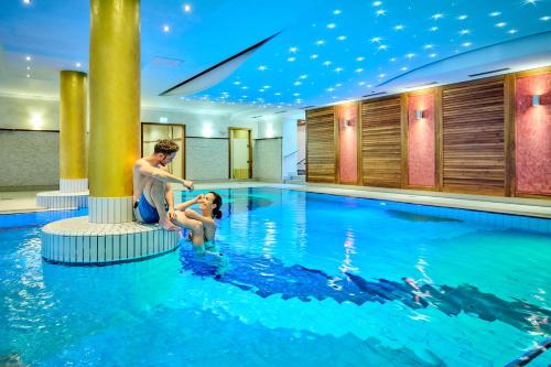 a man and a woman sitting in a swimming pool at Vitalhotel Bad Birnbach in Bad Birnbach