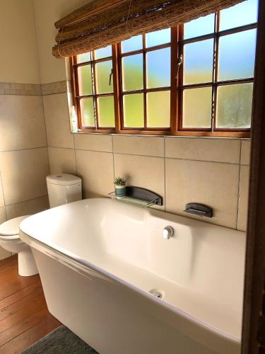 a white bath tub in a bathroom with a toilet at Hope Haven Cottage in Nelspruit