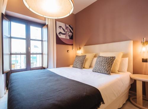 1 dormitorio con 1 cama grande y ventana grande en Suites Triana Sevilla Apartments en Sevilla
