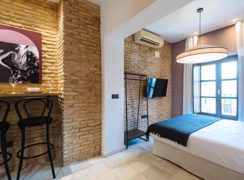 a bedroom with a brick wall and a bed and a desk at Suites Triana Sevilla Apartments in Seville