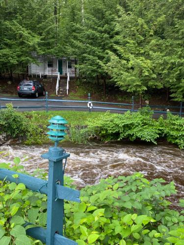 a blue fence next to a river with a car at Brookside Motel & Cabins in Lake George