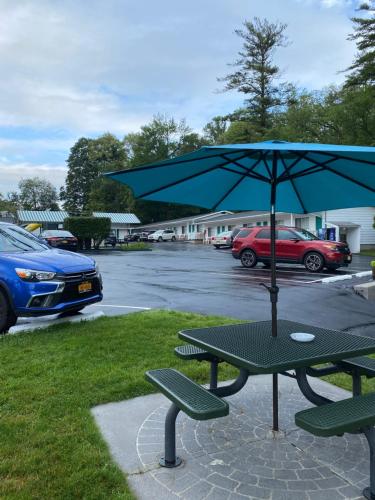 a picnic table with an umbrella in a parking lot at Brookside Motel & Cabins in Lake George