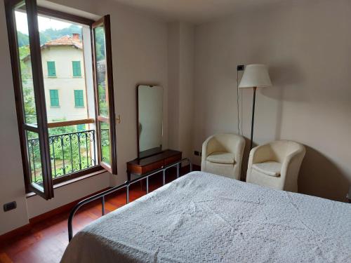 een slaapkamer met 2 stoelen, een bed en een raam bij Locanda del Brinsc in Brinzio