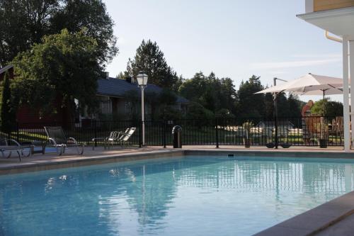 a swimming pool with chairs and an umbrella at Hestraviken Hotell & Spa in Hestra
