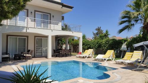 a villa with a swimming pool and lounge chairs at Villa Jasmin in Fethiye