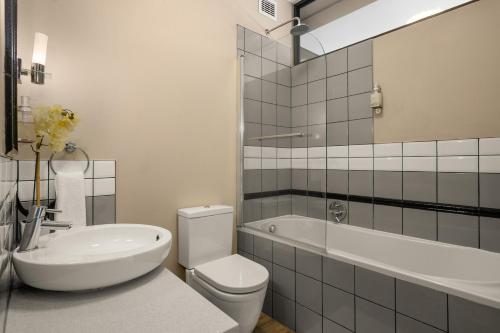 a bathroom with a toilet and a sink and a tub at Easy Stay - The Vantage Rosebank in Johannesburg