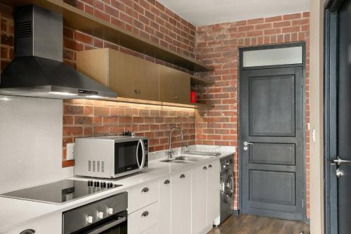 a kitchen with white cabinets and a brick wall at Easy Stay - The Vantage Rosebank in Johannesburg