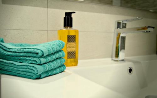 a bathroom sink with a stack of towels and a bottle of soap at Corralejo Sun 103 wifi free in Corralejo