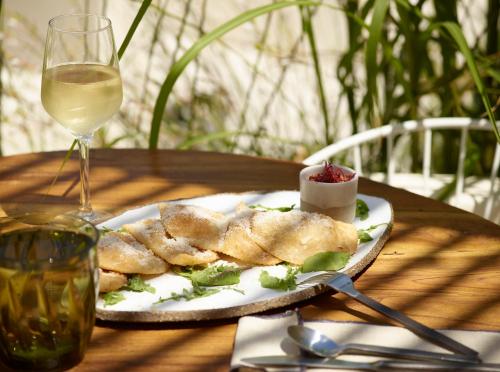 a plate of food on a table with a glass of wine at White Pebble Suites in Pollonia
