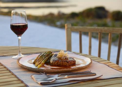 a plate of food and a glass of wine on a table at White Pebble Suites in Pollonia