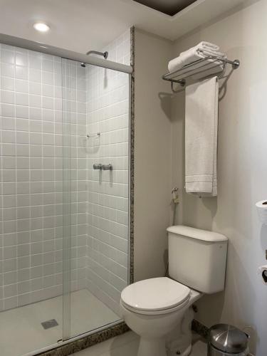 uma casa de banho com um WC e uma cabina de duche em vidro. em Flat IATE CLUBE Home Experience Praia do Canto em Vitória