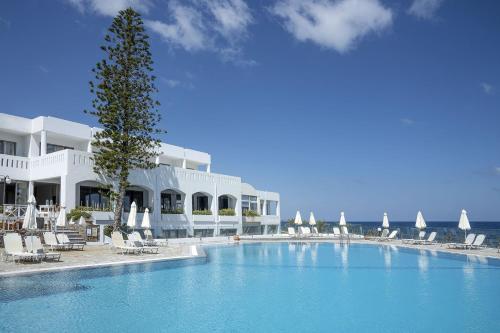 a swimming pool in front of a hotel with chairs at Maritimo Beach Hotel in Sisi