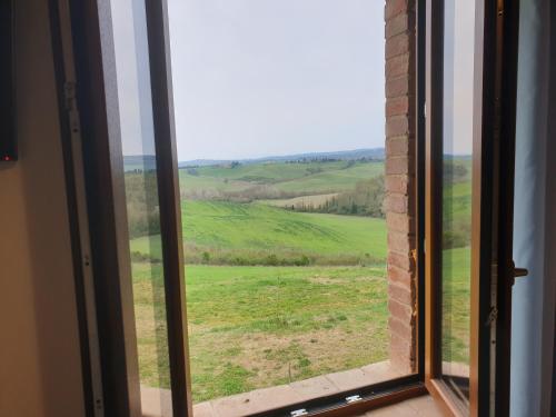 une fenêtre avec vue sur un champ verdoyant dans l'établissement Podere Fogliano, à Sienne