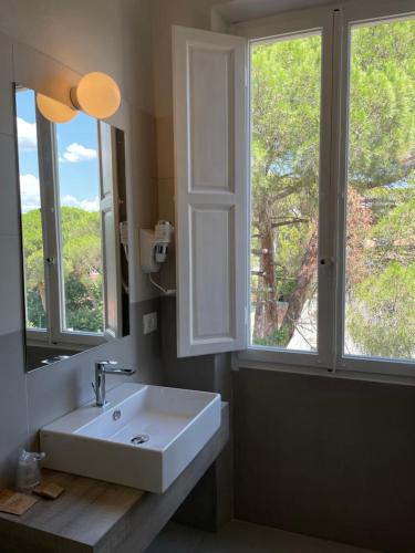baño con lavabo blanco y 2 ventanas en Guerrini Hotel, en Castiglioncello