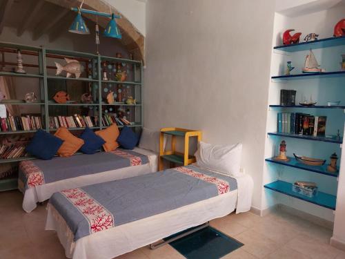 Pokój z 2 łóżkami i półką na książki w obiekcie Tipica casa marinara carlofortina w mieście Carloforte