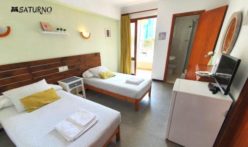 um quarto de hotel com duas camas e uma televisão em Saturno em Cala Millor