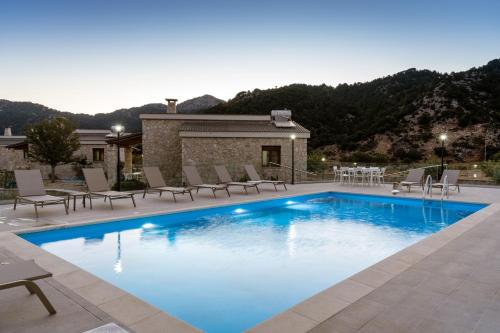 a swimming pool with chairs and a house at Omalos Village in Omalós