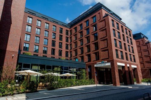 a tall building with a red brick building behind it at Motel One Hamburg-Fleetinsel in Hamburg