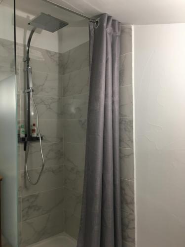 a shower with a gray shower curtain in a bathroom at Campagne et océan in Ahetze