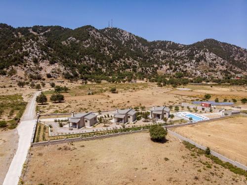 an aerial view of a house in a field with a mountain at Omalos Village in Omalós
