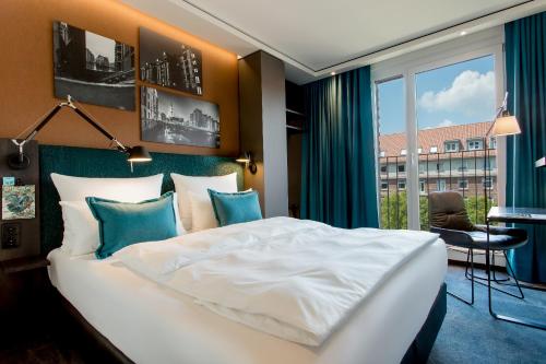 a hotel room with a large bed and a large window at Motel One Hamburg-Fleetinsel in Hamburg