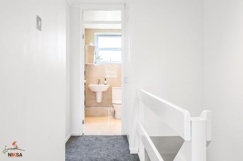 a white bathroom with a sink and a toilet at NIKSA Serviced Accommodation - 3 bedroom house in Welwyn Garden City