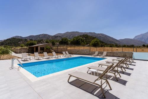 a pool with chaise lounge chairs and a swimming pool at Omalos Village in Omalós