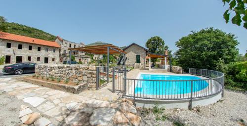 a swimming pool in a yard with a stone wall at Villa Rosa in Ravno
