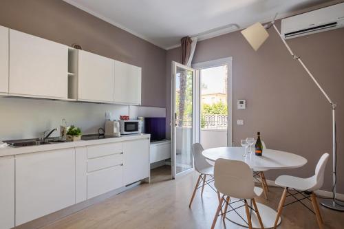 uma cozinha com armários brancos e uma mesa com cadeiras em MyPlace Padova Porta San Giovanni em Pádua
