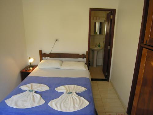 a bedroom with a bed with two dresses on it at Jabaquara Beach Resort in Paraty