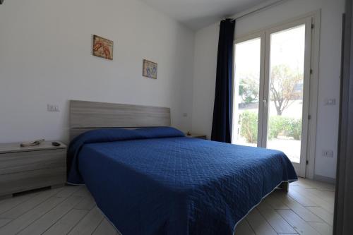 sypialnia z niebieskim łóżkiem i oknem w obiekcie Isola Rossa Elite w mieście Trinità dʼAgultu