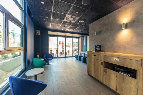 a waiting room with blue chairs and a large window at ibis budget Huerta De Murcia in Murcia