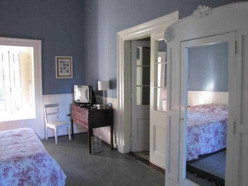 a bedroom with two beds and a desk with a television at Hotel Plaza Malloa in Malloa