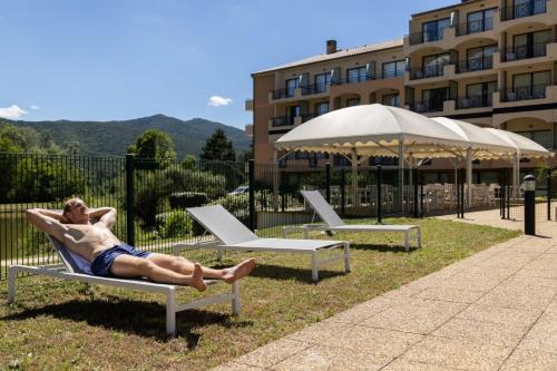 a man laying on a chair in the grass at Domaine Les Sources de Dieulefit in Dieulefit