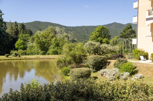 a garden with a lake and mountains in the background at Domaine Les Sources de Dieulefit in Dieulefit