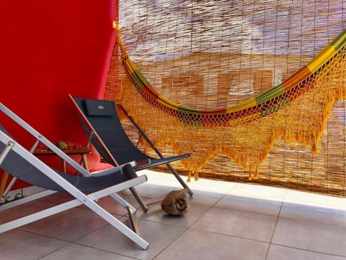 two chairs and a hammock in front of a wall at Zandoli Cottage in Les Galets
