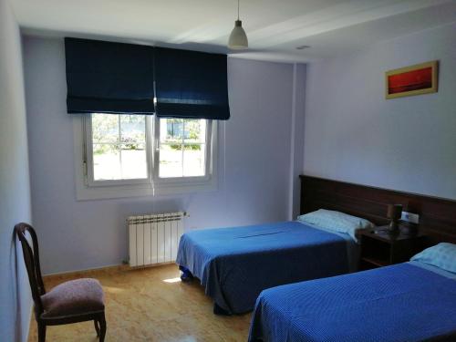 1 dormitorio con 2 camas y ventana en Apartamentos Turísticos San Breixo, en Carballo