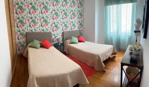 2 camas en una habitación con papel pintado floral en APARTAMENTO ANOVA, en Padrón