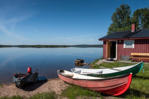 two boats sitting on the shore next to a house at Piilijärvi Camping in Gällivare