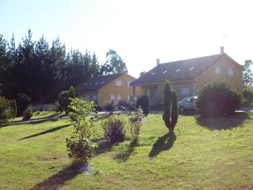 a yard with a house and some plants in the grass at Apartamentos Turísticos San Breixo in Carballo