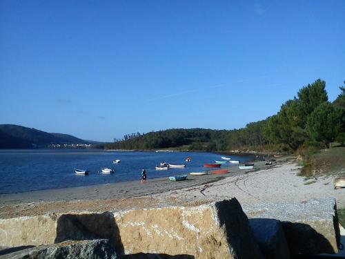 a beach with boats in the water and a group of people at Apartamentos Turísticos San Breixo in Carballo