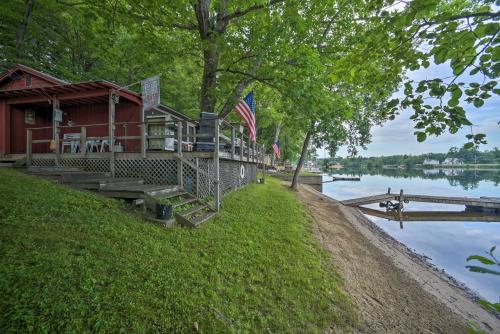 a building on the shore of a lake with an american flag at Riverfront Escape with Dock 19 Mi to Saratoga! in Lake Luzerne