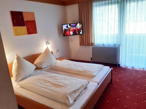 a bedroom with two beds and a tv on the wall at Gästehaus Bräuer in Neukirchen am Großvenediger