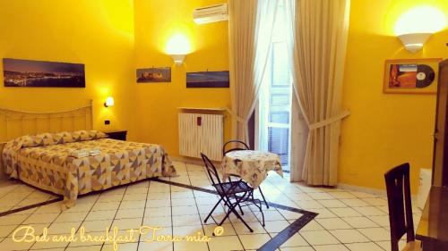um quarto amarelo com uma cama e uma mesa em B&B Terra Mia Napoli em Nápoles